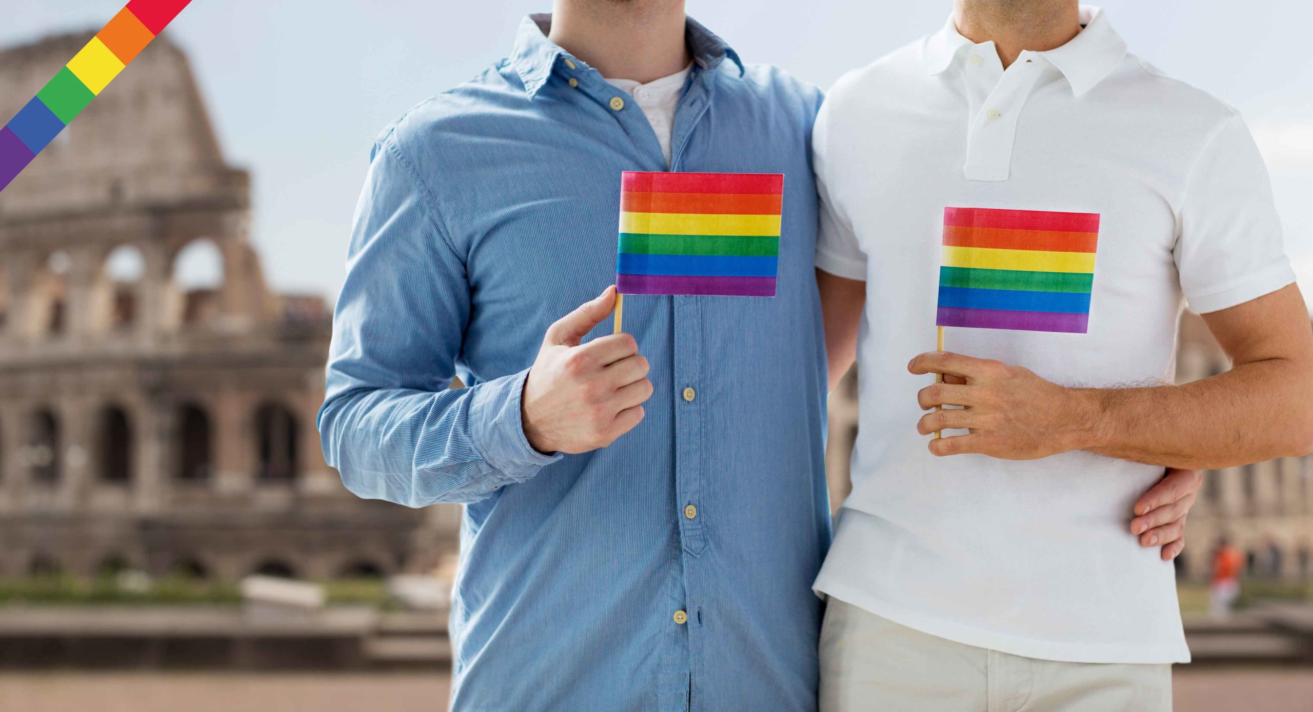 people, homosexuality, same-sex marriage, travel and love concept - close up of happy male gay couple holding rainbow flags and hugging from back over coliseum in rome background